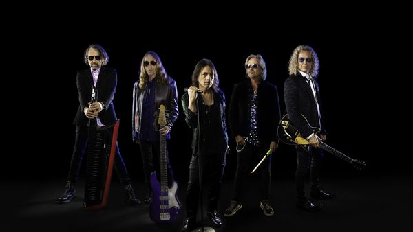 Die Band Foreigner vor einem dunklen Hintergrund als Gruppenfoto
