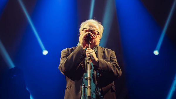 Heinz-Rudolf Kunze am Mikrofon bei einem seiner Auftritte mit blauem Licht im Hintergrund