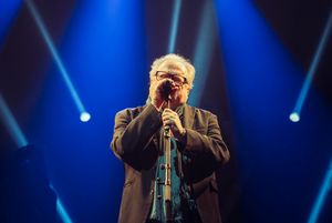 Heinz-Rudolf Kunze am Mikrofon bei einem seiner Auftritte mit blauem Licht im Hintergrund