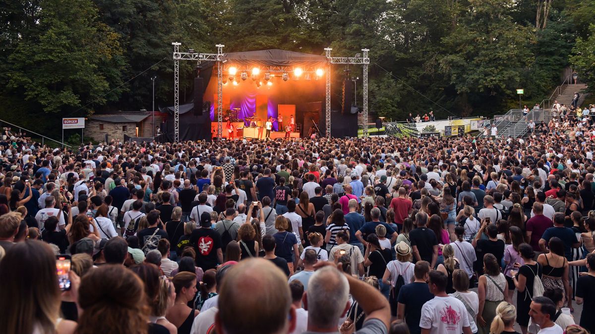 Eine große Menschenmenge steht vor der BÜRGER Freilichtbühne und feiert mit Clueso, der auf der Bühne singt und performt.