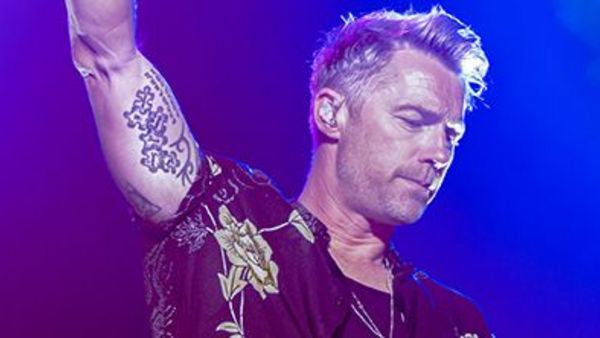 Ronan Keating bei einem seiner Auftritte auf einer Bühne, von hinten mit blauem Licht angestrahlt