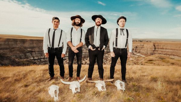 Die vier Band-Mitglieder von The Dead South stehen nebeneinander in einer Steppe mit vier Büffel-Schädeln vor sich