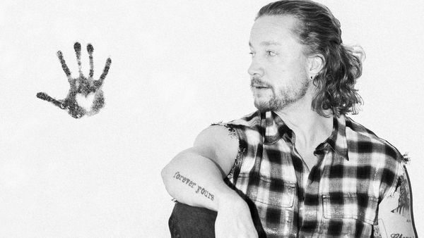 Samu Haber Promo-Bild in Schwarz-Weiß, sitzend an einer Wand mit Handabdruck mit Herz an der Wand