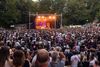 Frontaler Blick auf die BÜRGER Freilichtbühne. Menschen feiern in der Dämmerung vor der Bühne.